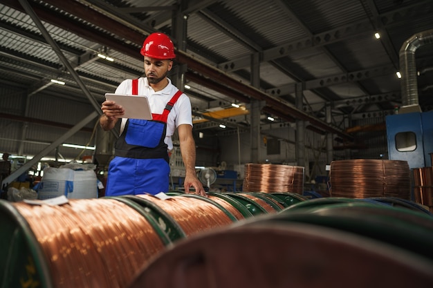 African american male manager in electric cable warehouse holding digital tablet