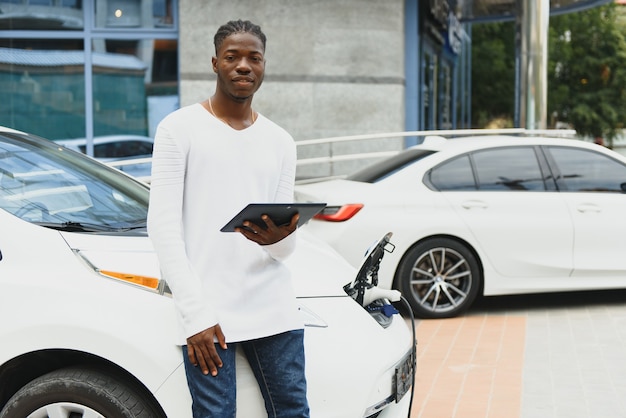 African American man charging his electric car.