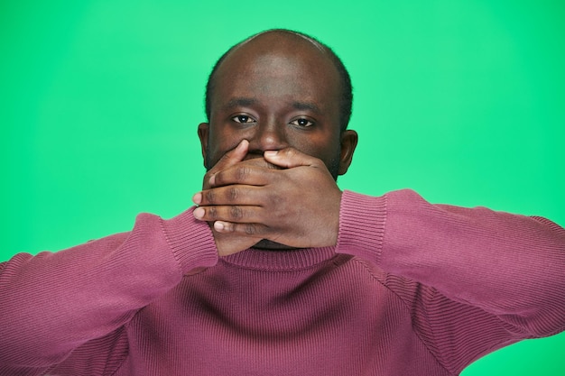 African American man closing his mouth with hands