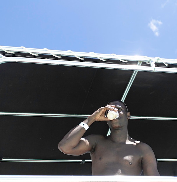 African American man drinking in beach gazebo