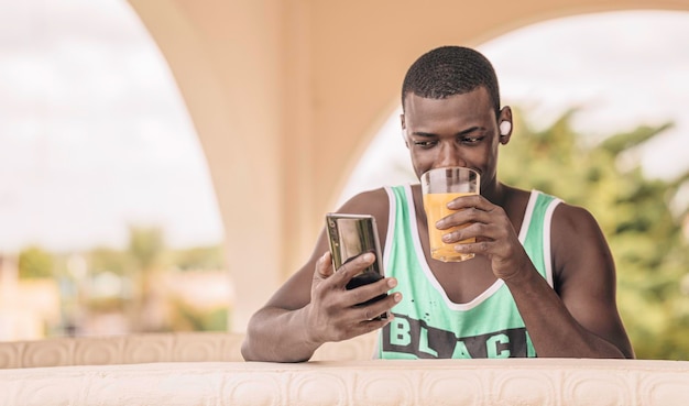 African American man drinking juice and using cellphone