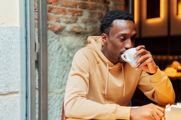 African american man enjoying and drinking a coffee while sitting at coffee shop