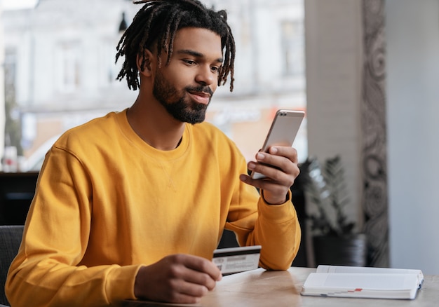 African American man holding credit card, ordering food online