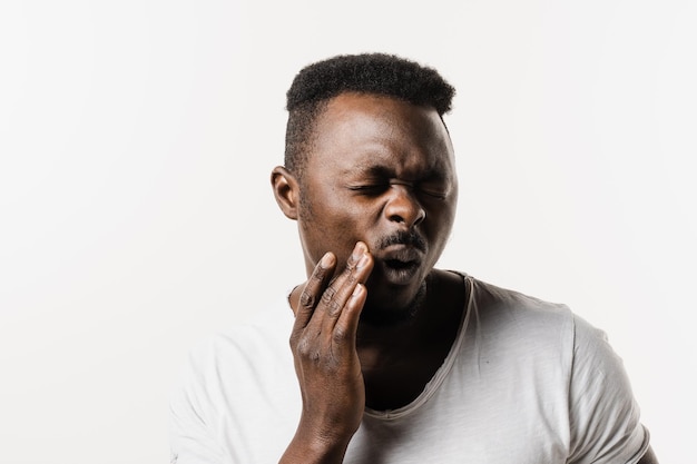 African american man is touching cheek and feeling toothache pain and discomfort of tooth African man with tooth decay infection or injury to the tooth or gums on white background