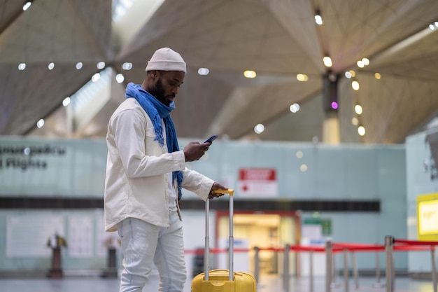 African American man passenger looking at mobile boarding pass on smartphone in checkin area