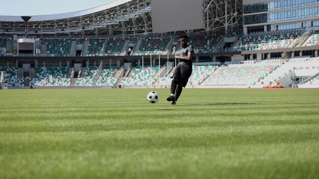 African American man playing football on the stadium field A man runs with a soccer ball across the field