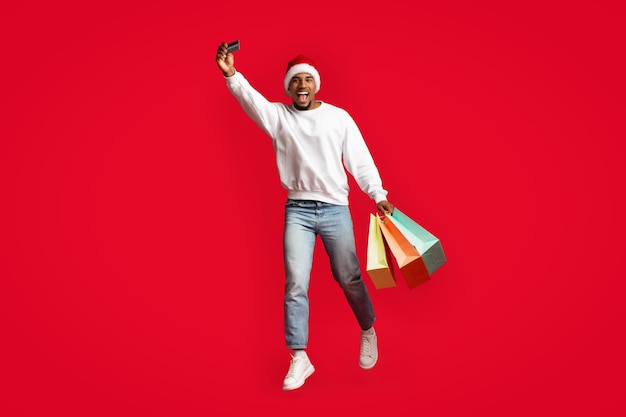 African american man Santa Claus holding purchases and credit card