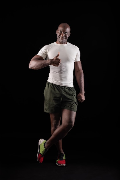 African American man standing looking at camera with thumb up and one leg crossed