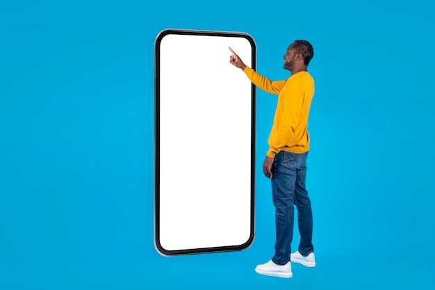 African american man touching big smartphone screen mockup full length