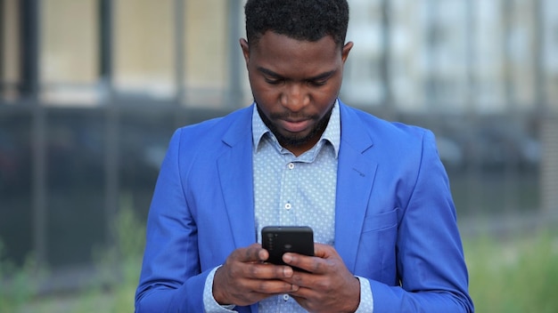 African american man types messages to workers on phone