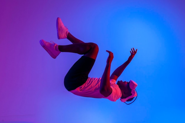 Photo african american man in virtual reality glasses flies in the air and touches the imaginary in neon