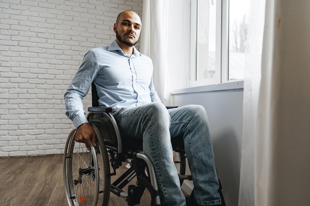 African american man in wheelchair sitting near the window alone at home