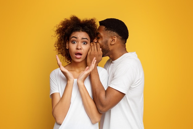 African american man whispering to shocked girlfriend