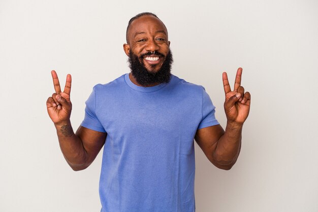 African american man with beard isolated on pink wall showing victory sign and smiling broadly.