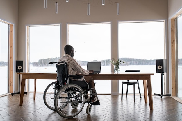 African american man with disability working in front of laptop by table