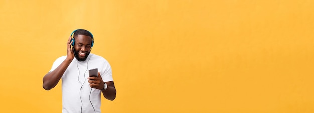 African american man with headphones listen and dance with music isolated on yellow background