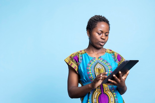 African american modern girl feels satisfied using a tablet over blue background