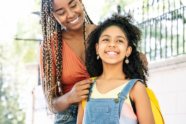 African American mother taking her daughter to the school. Education concept.