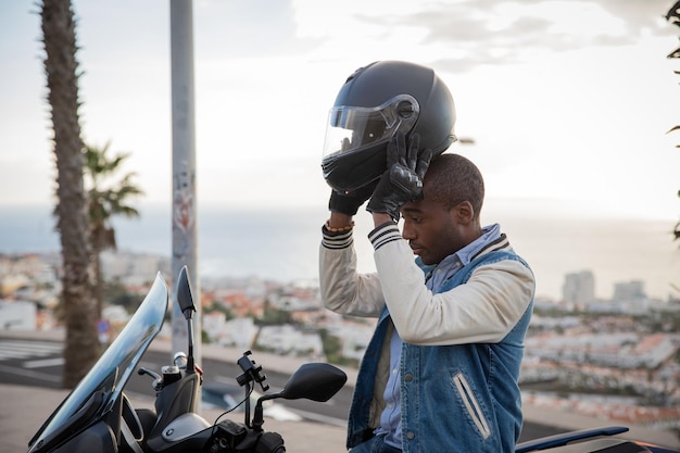 African American motorcyclist wears a helmet while sitting on his motorcycle