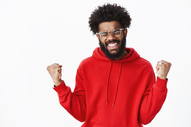 african american musician raising fists in victory gesture smiling, clenching teeth in joy and close eyes as celebrating victory and triumph.