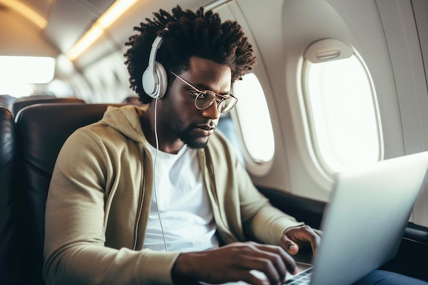 African American passenger with laptop and headphones on airplane