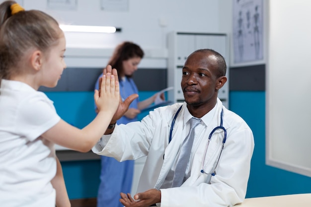 African american pediatrician doctor giving high five to young children