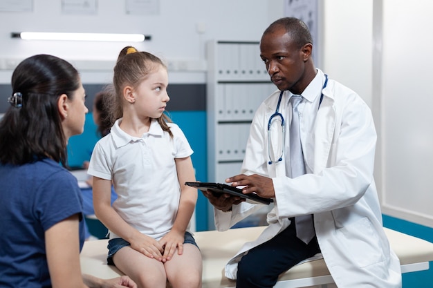 African american pediatrician doctor typing disease expertise of young child