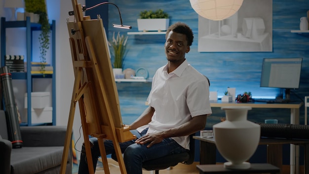 African american person sitting in art studio with drawings and easel, creating professional masterpiece of vase. Black artist man with craft equipment and pencils for authentic artwork