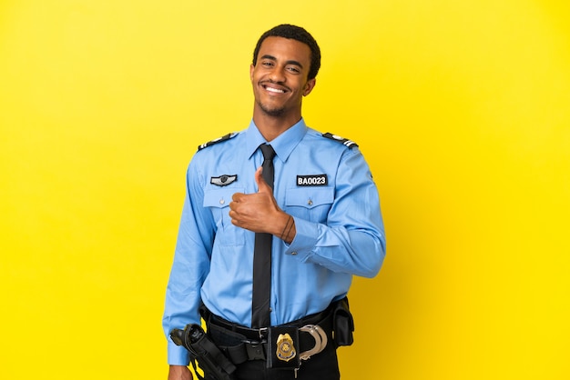 African American police man over isolated yellow background giving a thumbs up gesture