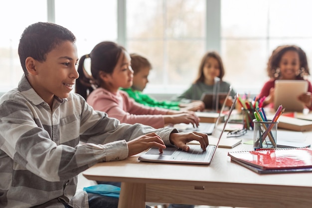 African American Schoolboy Using Laptop Computer Learning Online At School