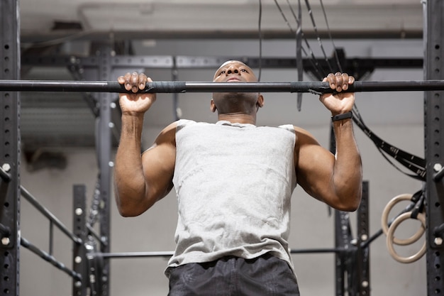 African American sportsman doing physical exercise on fixed bar. Fitness training in gym.