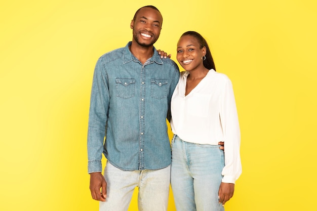 African American Spouses Embracing On Yellow Studio Background