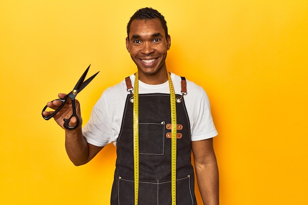 African American tailor with scissors and tape yellow studio backdrop