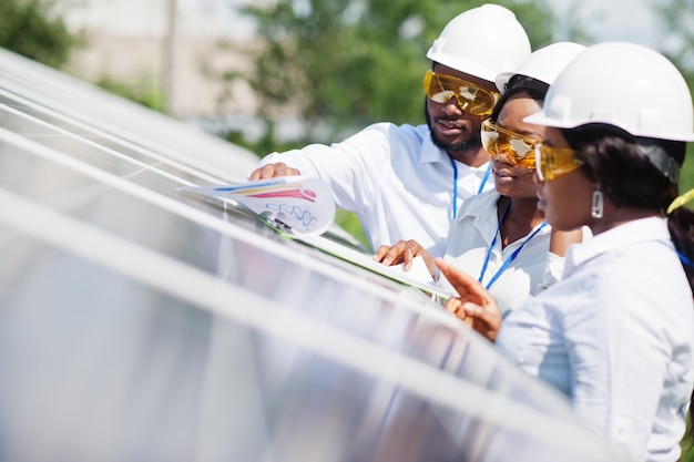 African american technician checks the maintenance of the solar panels. Group of three black engineers meeting at solar station.