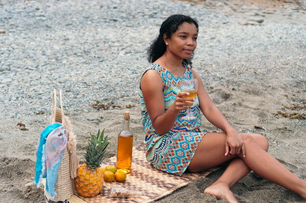 African American Woman drinking a glass of wine on the beach