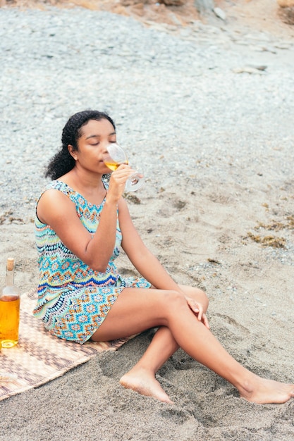 African American Woman enjoying a glass of wine on the beach in the morning