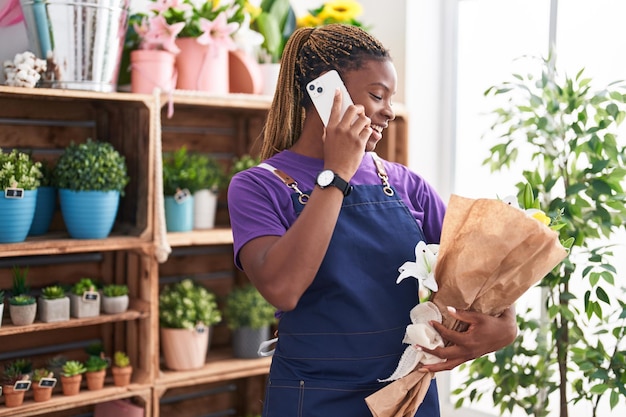 African american woman florist talking on smartphone holding flowers at florist