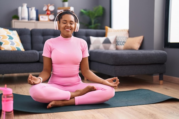 African american woman listening to music doing yoga exercise at home