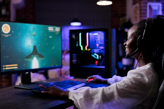 African american woman playing shooting video games on pc, having fun with action rpg competition on live stream. Female gamer enjoying shooter tournament online on streaming competition.