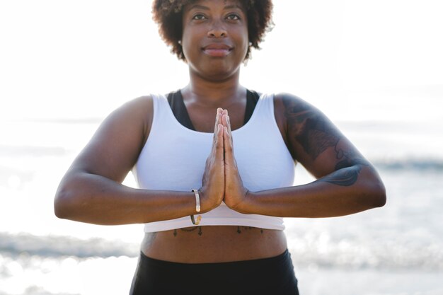 African American woman practicing yoga at the beach