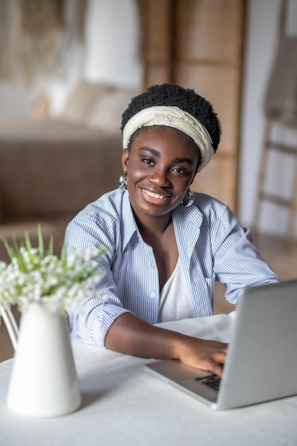 African american woman sitting at the table and working on a laptop