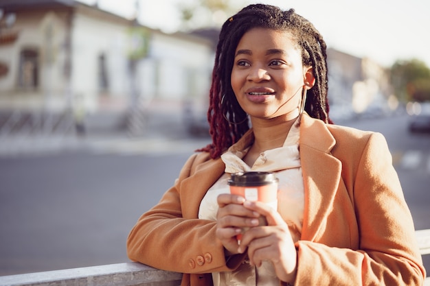 African american woman standing in a srteet with takeaway coffee cup