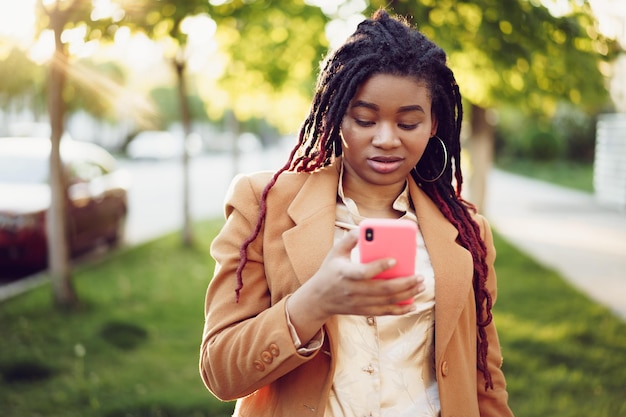 African american woman standing in a street and using smartphone