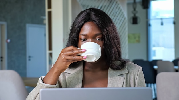 African-American woman talks on videochat via laptop in cafe