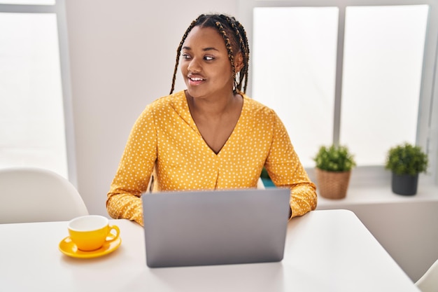 African american woman using laptop drinking coffee at home