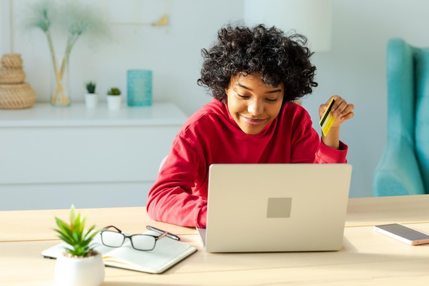 African american woman using laptop shopping online paying with gold credit card girl sitting at