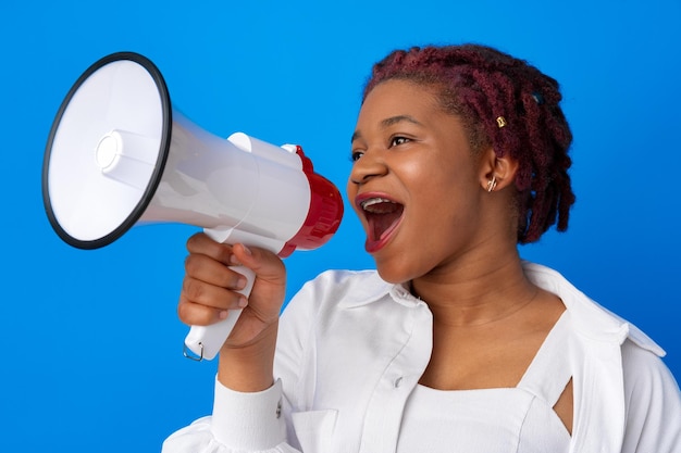 African american woman using megaphone against blue background