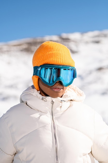 An African American woman wearing snow goggles on a snowy mountain during winter