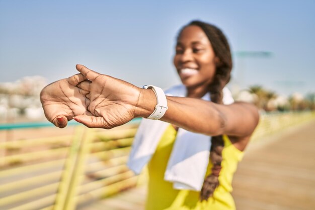 African american woman wearing sportswear stretching arm at street