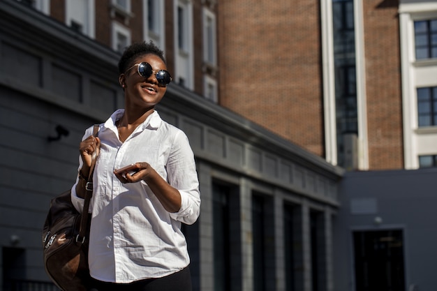 African american woman with backpack walking outdoor and talking on mobile phone